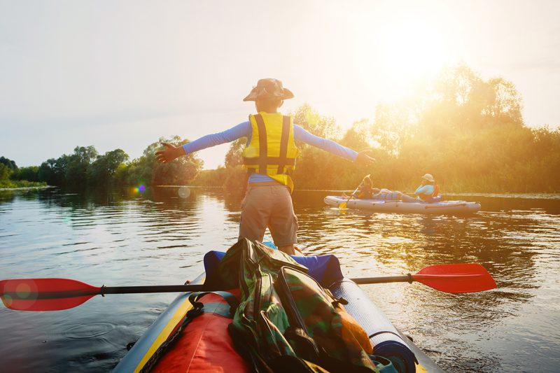 Happy boy kayaking on the river. Active boy having fun enjoying adventurous experience with kayak On the Sunset during summer vacation