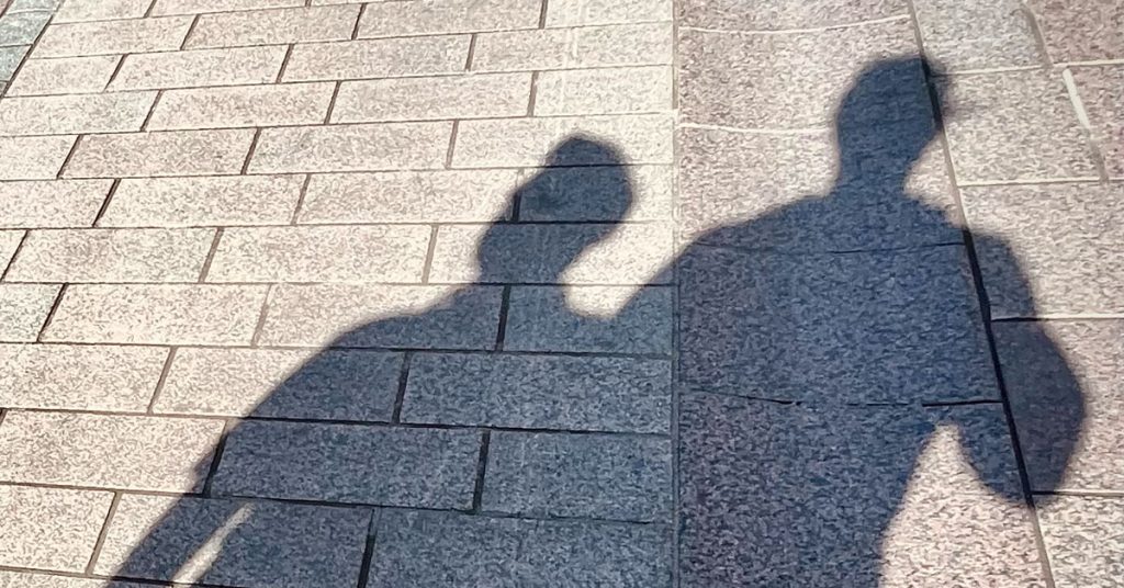 kahden henkilön varjot näkyvät katukiveyksellä.
