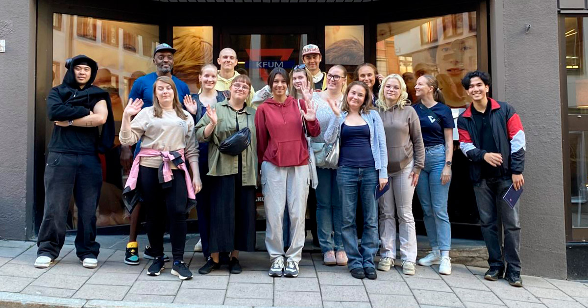 ymca-nmky-finymca9-johtajuuskoulutus-1200x627 FINYMCA-johtajuuskoulutuksen nuoret seisovat KFUM Centralin edessä.